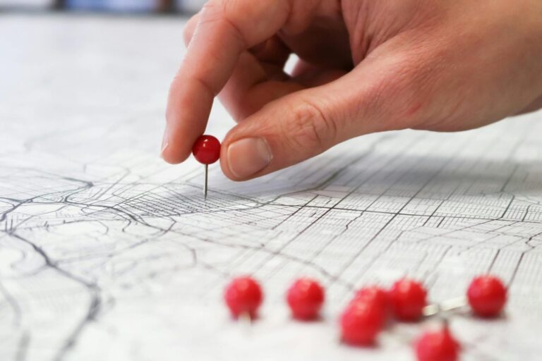 Red pin being placed on a map to mark a current position, representing where we are now.